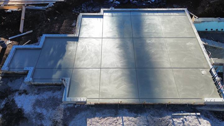 Overhead view of a finished slab pour, hand-troweled and jointed into panels with the forms still in place — Truckee area