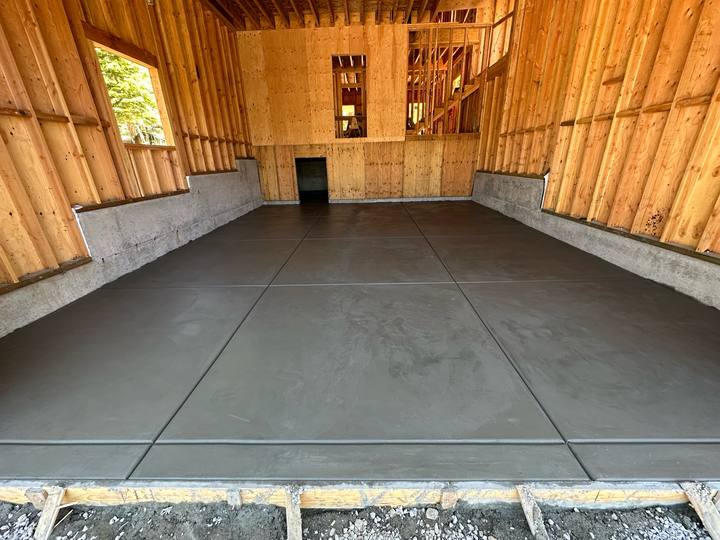 A finished interior garage slab, steel-troweled smooth and saw-cut into panels, inside a framed and sheathed building