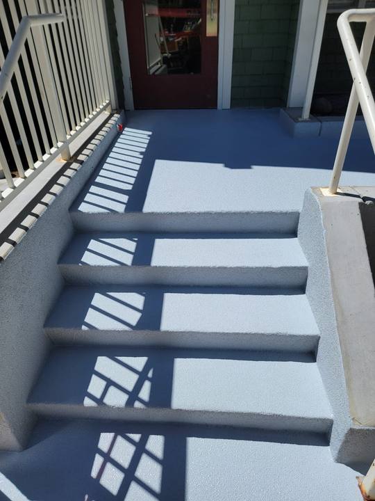 A commercial entry landing and steps after resurfacing, in a two-tone grey non-slip coating that runs up the risers and out to the edge