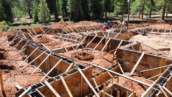 Overhead view of a large foundation in wall forms — dozens of braced panels laid out across the excavation with the crew working the far side