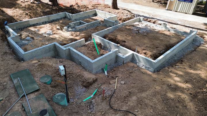 Overhead view of a finished stem-wall foundation, every wall poured and stripped and the interior pads set